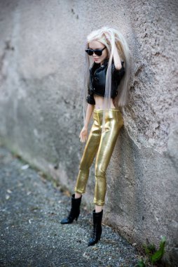 Mulhouse - Fransa - 21 Nisan 2021 - Siyah deri ceketli, güneş gözlüklü ve sokakta duran altın tozluklu sarışın Barbie bebek portresi