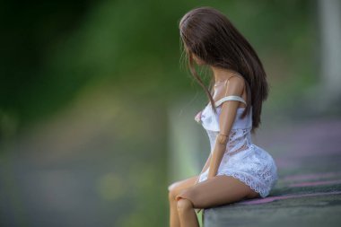  Beyaz şeffaf geceliğin yakın çekimi. Esmer manken bebek sokakta oturuyor.