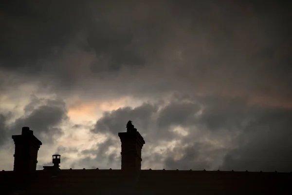 stock image Closeup of chimneys silhouettes an crow silhouettte  on dramatic sky by sunset background