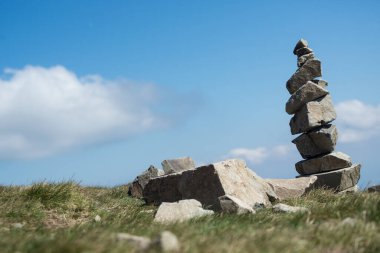 Mavi gökyüzü arka planında, dağın tepesindeki taş dengesi.