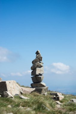 Mavi gökyüzü arka planında, dağın tepesindeki taş dengesi.