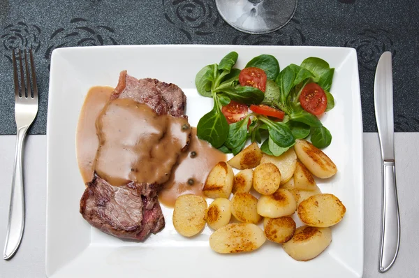 Filete a la parrilla con salsa de pimienta y patatas y tomates cherry mache — Foto de Stock