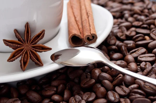 Cup of coffee with dried anise and cinnamon on beans background — Stock Photo, Image