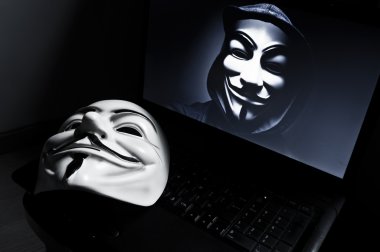 Paris - France - 18 January 2015 - Vendetta mask on computeur with an anonymous member on screen, . This mask is a well-known symbol for the online hacktivist group Anonymous clipart