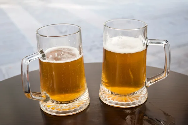 Dos tazas de cerveza en una mesa de bar — Foto de Stock