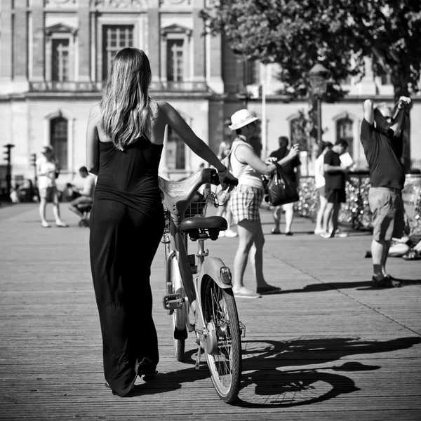 ПАРИЖ - Франция - 23 июля 2012 года - женщина, гуляющая на велосипеде по мосту искусств в Париже — стоковое фото