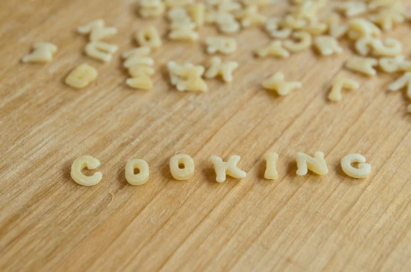 Cozinhar macarrão alfabeto em fundo de madeira — Fotografia de Stock