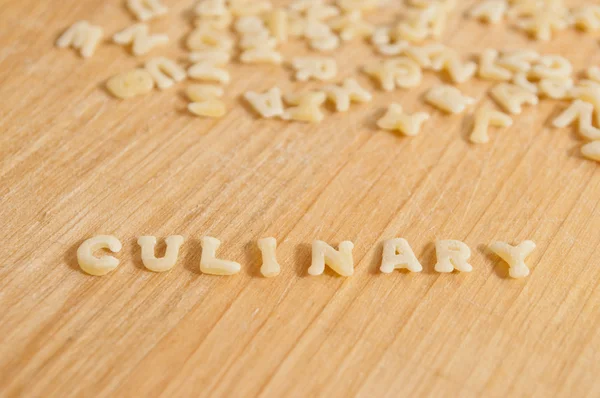 Pasta del alfabeto que forma el texto "culinario" sobre fondo de madera — Foto de Stock