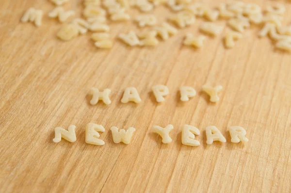 Alphabet pâtes formant le texte "Bonne année" sur fond de bois — Photo