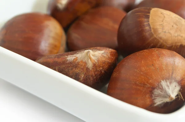 Grupo close-up de castanhas em uma tigela no fundo branco — Fotografia de Stock