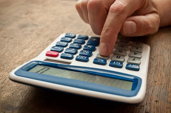 Primer plano oh mano con calculadora sobre fondo de escritorio de madera —  Fotos de Stock