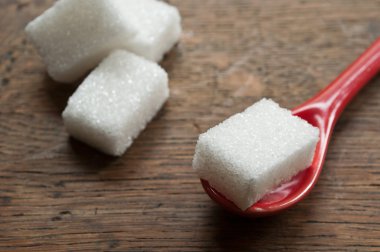 ahşap arka plan üzerinde kırmızı bir kaşık şeker küplerinde closeup