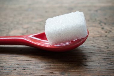 ahşap arka plan üzerinde kırmızı bir kaşık şeker küpü closeup