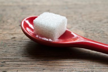 ahşap arka plan üzerinde kırmızı bir kaşık şeker küpü closeup