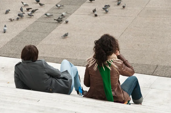 คู่รักนั่งอยู่บนบันไดในอาคารกลาโหมในปารีส — ภาพถ่ายสต็อก