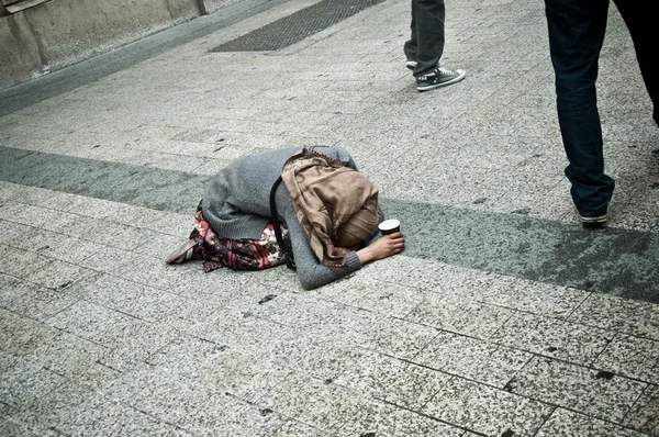 poor woman kneeling in the street of Paris