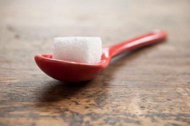 ahşap arka plan üzerinde kırmızı bir kaşık şeker küpü closeup