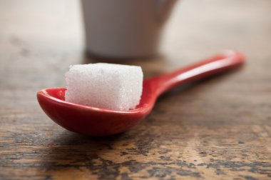 ahşap arka plan üzerinde kırmızı bir kaşık şeker küpü closeup