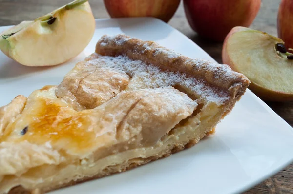 Closeup of apple pie with raw apples on wooden table — Stock Photo, Image