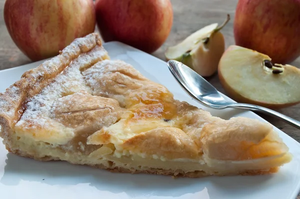 Closeup of apple pie with raw apples on wooden table — Stock Photo, Image