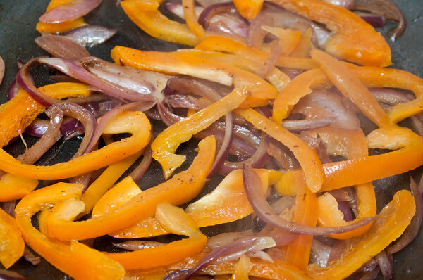 closeup of orange pepper and onions cooking