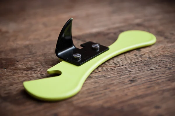 Closeup of can opener on wooden background — Stock Photo, Image