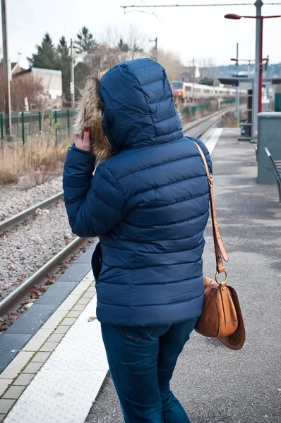 Vrouw te wachten de trein met gans veren jasje — Stockfoto