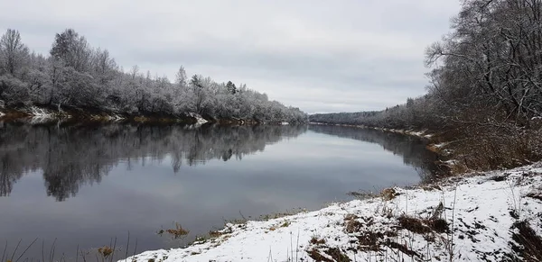 Winterliche Flusslandschaft. Der natürliche Hintergrund. Winterurlaub im Hintergrund. Das Ufer spiegelt sich im Fluss wider. Schöner Fluss im Winter. Blauer Himmel. Schneebäume. Russland im Winter. Wildtiere. — Stockfoto