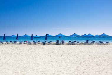 Birçok plaj sandalyeleri ve mavi gökyüzü ile beyaz deniz kum plajda şemsiye. Dinlenme, rahatlama, tatil, spa, resort konsepti.