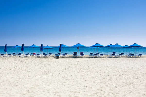 Birçok plaj sandalyeleri ve mavi gökyüzü ile beyaz deniz kum plajda şemsiye. Dinlenme, rahatlama, tatil, spa, resort konsepti.