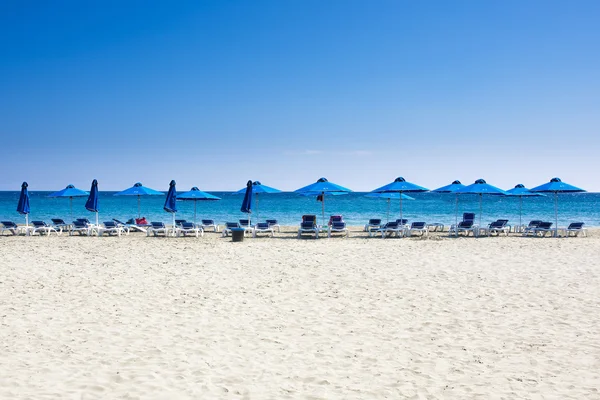 Vele strandstoelen en parasols op wit zand strand met een blauwe lucht. Concept voor rust, ontspanning, vakantie, spa, resort. — Stockfoto