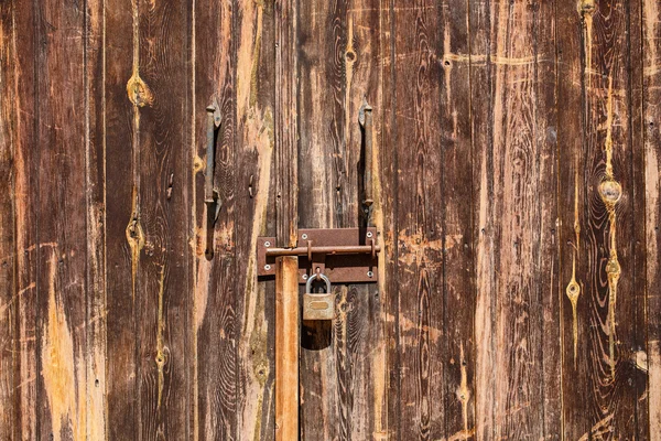 Old wooden door with scratches texture and a hanging lock. — Stock Photo, Image