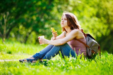 Onun smartphone kullanarak ve kahve bir parkta olan kadın.