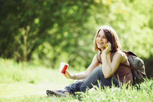 Smartphone üzerinde konuşmak ve kahve bir parkta olan kadın.