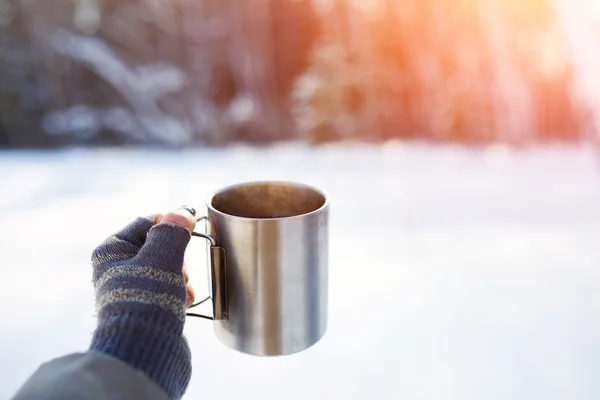 Gloved mitten hand holding a travel mug.