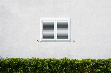 Pencere kepenkleri, beyaz duvar ile.