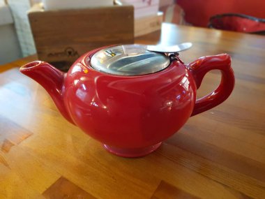 Kırmızı çaydanlık, ahşap bir masanın üzerinde.