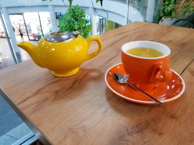 Çaydanlık ve kupa çay ahşap bir masada. Bir bardak deniz dikenli çay.