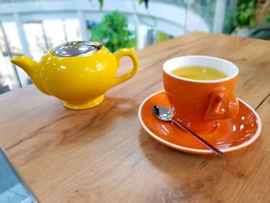 Çaydanlık ve kupa çay ahşap bir masada. Bir bardak deniz dikenli çay.