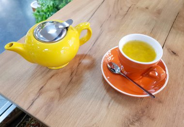 Çaydanlık ve kupa çay ahşap bir masada. Bir bardak deniz dikenli çay.