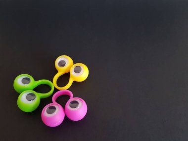 Konuşma terapisi oyuncakları siyah bir arka planda parmaklar üzerinde gözler