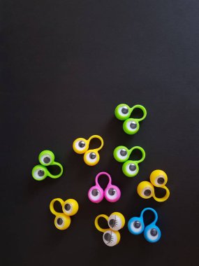 Konuşma terapisi oyuncakları siyah bir arka planda parmaklar üzerinde gözler