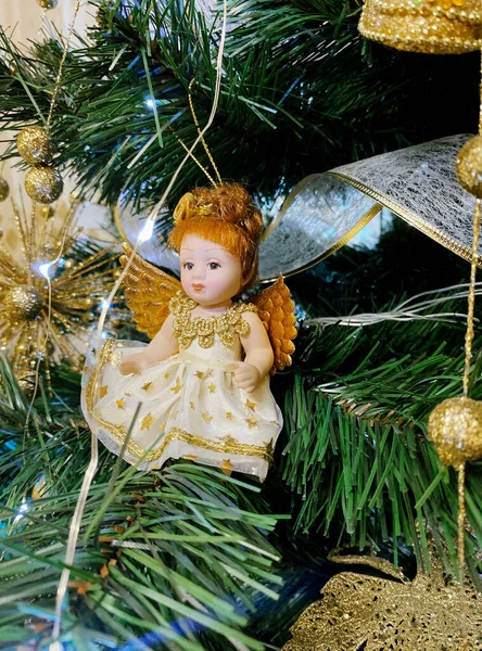 Christmas girl angel hanging on the Christmas tree. Angel decorates the Christmas tree