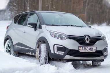 Grodno, Belarus-01.31.2021: Renault Capture or Renault Captur SUV on a winter road against the background of a field and forest. Winter driving conditions in Renault on a snowy road