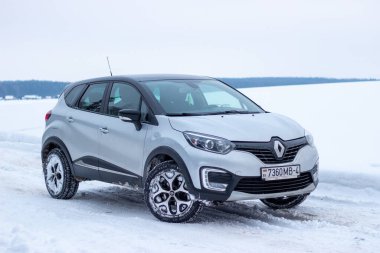 Grodno, Belarus-01.31.2021: Renault Capture or Renault Captur SUV on a winter road against the background of a field and forest. Winter driving conditions in Renault on a snowy road