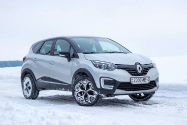 Grodno, Belarus-01.31.2021: Renault Capture or Renault Captur SUV on a winter road against the background of a field and forest. Winter driving conditions in Renault on a snowy road