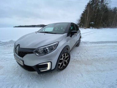 Grodno, Belarus-01.31.2021: Renault Capture or Renault Captur SUV on a winter road against the background of a field and forest. Winter driving conditions in Renault on a snowy road