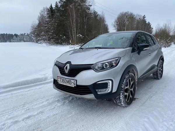Grodno, Belarus-01.31.2021: Renault Capture or Renault Captur SUV on a winter road against the background of a field and forest. Winter driving conditions in Renault on a snowy road