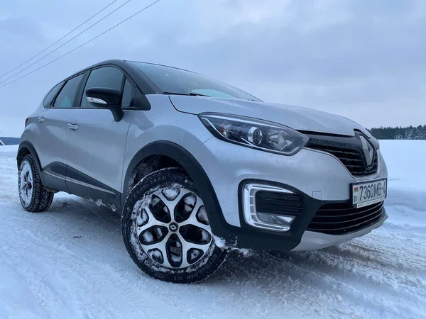 Grodno, Belarus-01.31.2021: Renault Capture or Renault Captur SUV on a winter road against the background of a field and forest. Winter driving conditions in Renault on a snowy road
