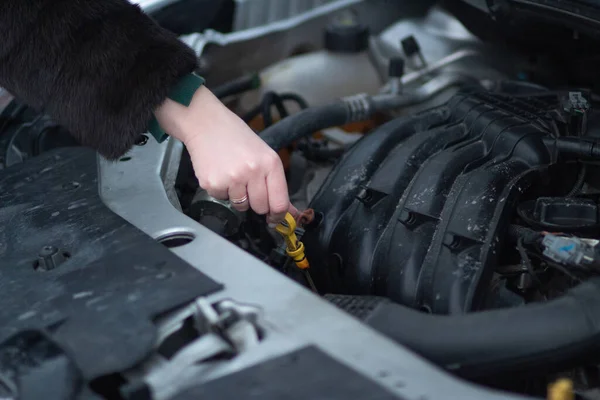 Woman checks the oil level in the car. Preparing the car for winter conditions